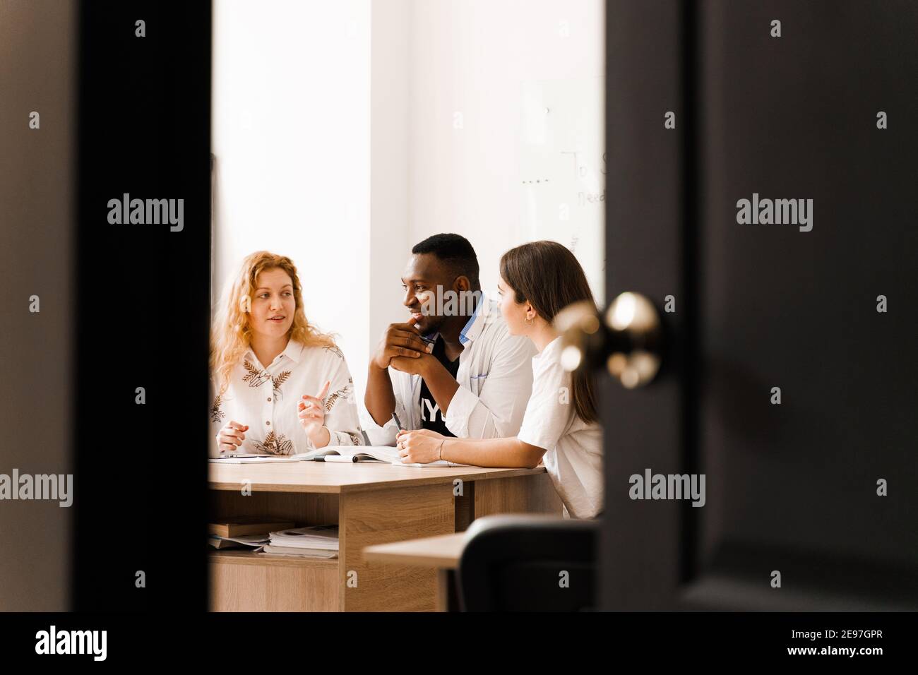 Online multiethnic attractive group of teachers study and laught, discuss something. Remote work in multinational group with laptop. Happy girls and b Stock Photo