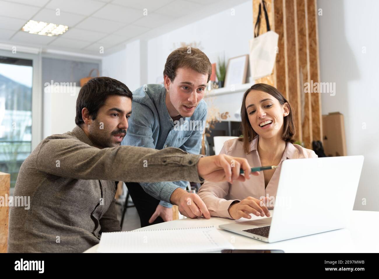 Three coworkers discussing and looking to a laptop. Stock Photo