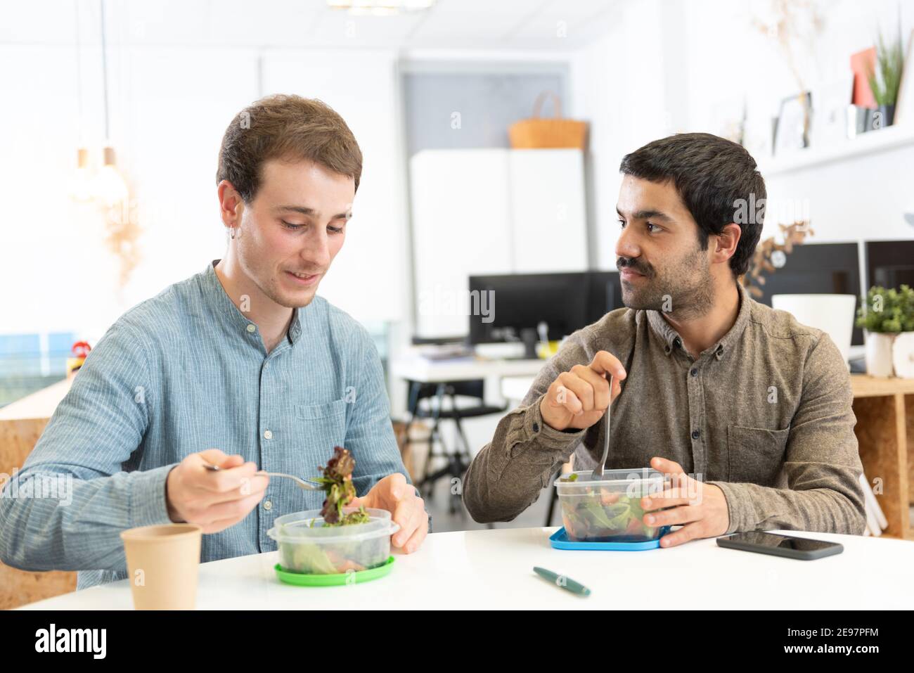 Healthy food in the workplace concept. Two coworkers having lunch in the office. Stock Photo