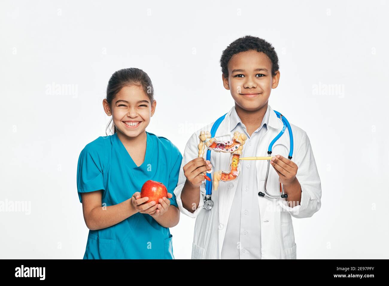 Fun multi-ethnic kids in medical uniforms are studying a human digestive system. Healthy food concept for children Stock Photo