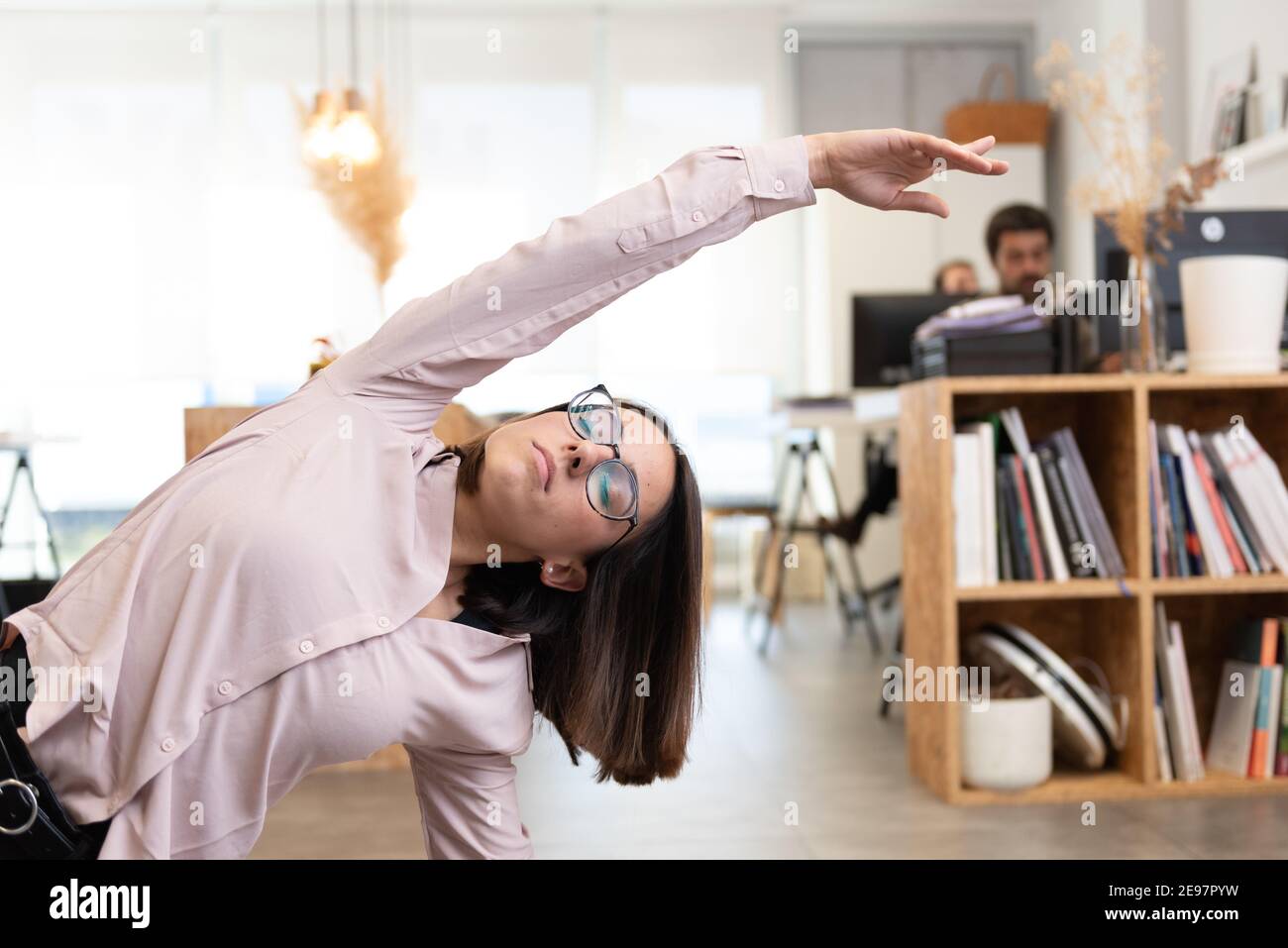 Hispanic female worker having a break to stretch and relax in the office. Stock Photo