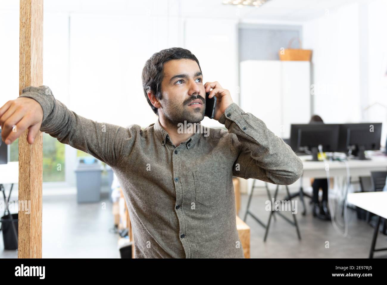 Confident hispanic man with mustache talking on the phone at the workplace. Stock Photo