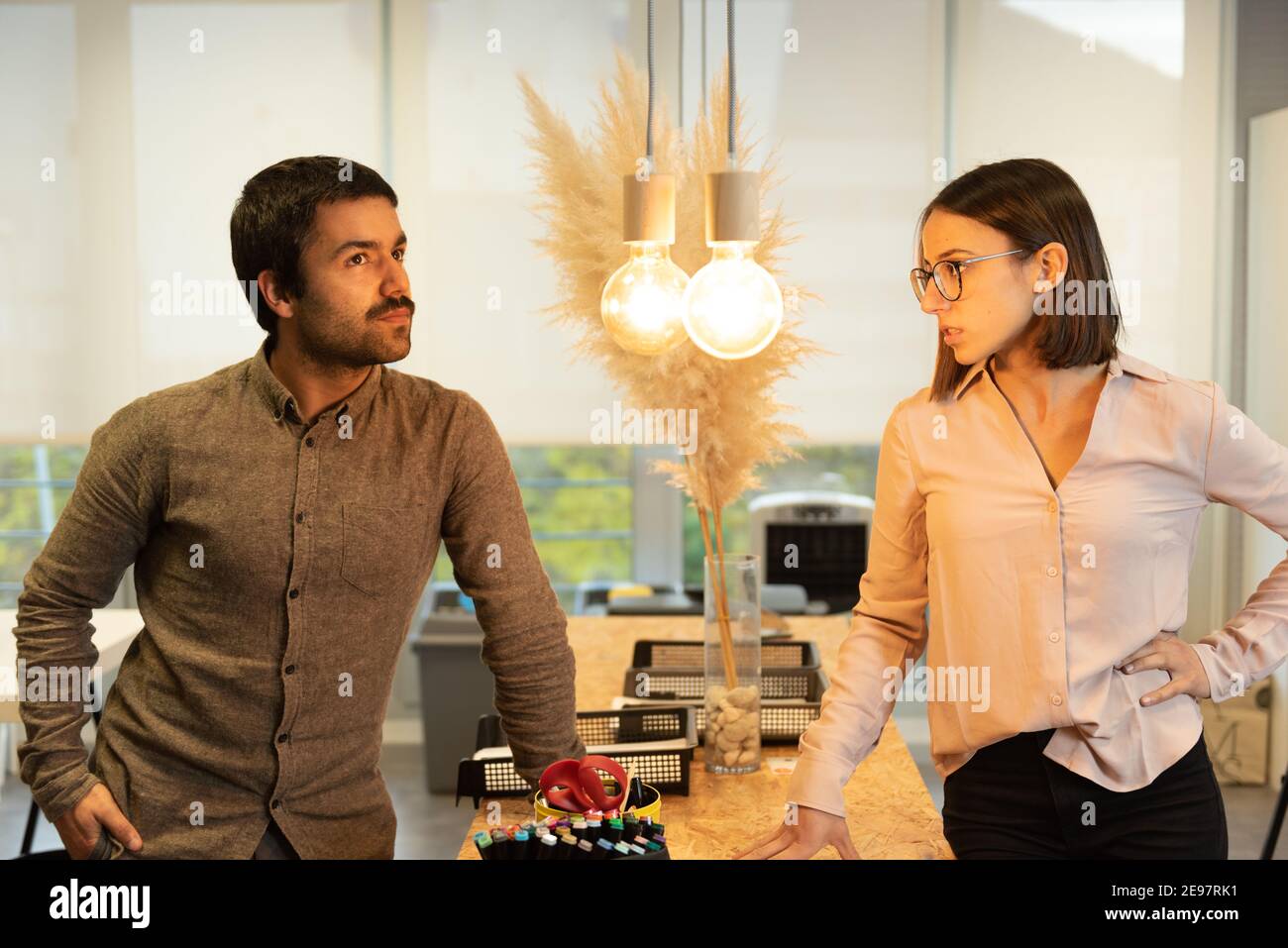 Informal chat of two hispanic coworkers while bulbs lighten them. Stock Photo