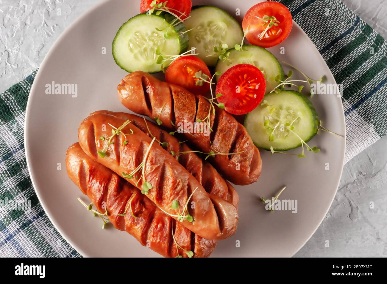 Grilled sausages with fresh vegetables are on the platter Stock Photo