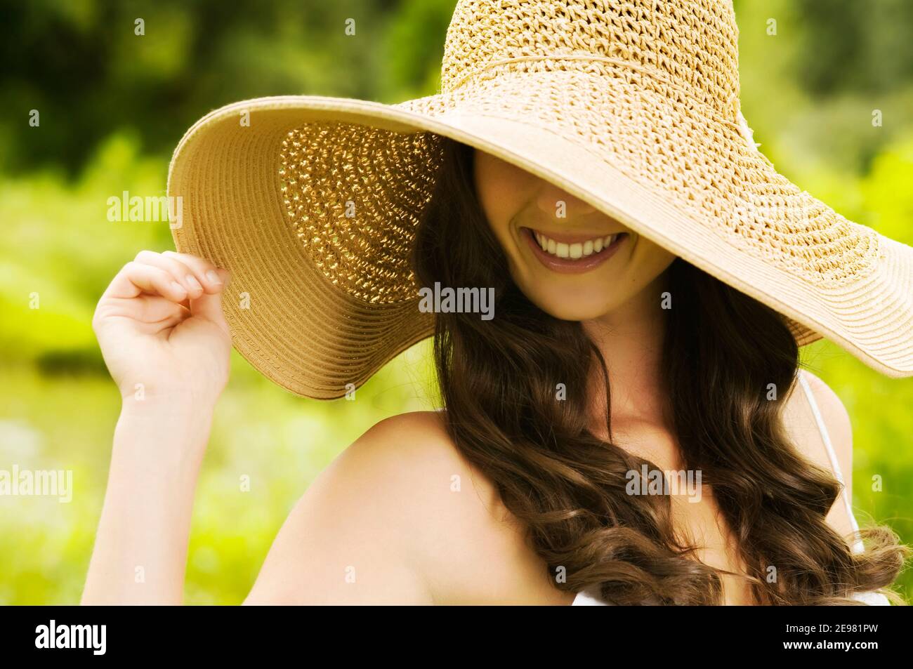 Smiling young woman in sun hat against background of summer green park — free download