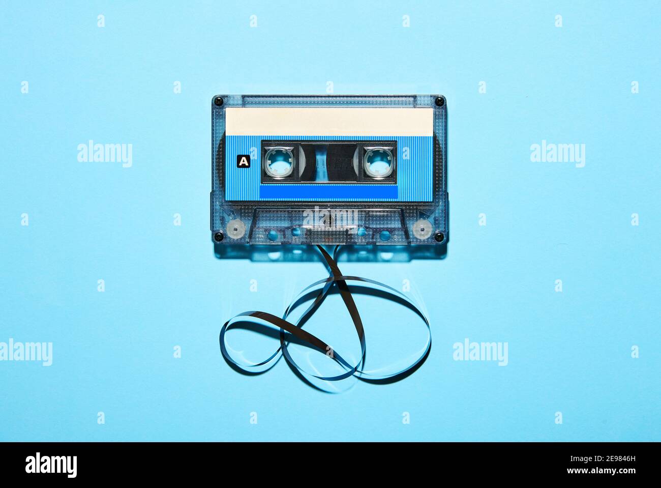 Top view of vintage old fashioned plastic compact audio cassette with tangled tape isolated on blue background Stock Photo