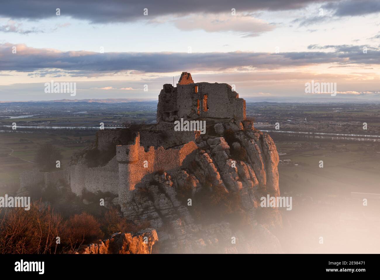 French winter landscapes. Stunning panoramic view of castle ruins Crussol. Foggy mountain landscape at sunrise. Stock Photo