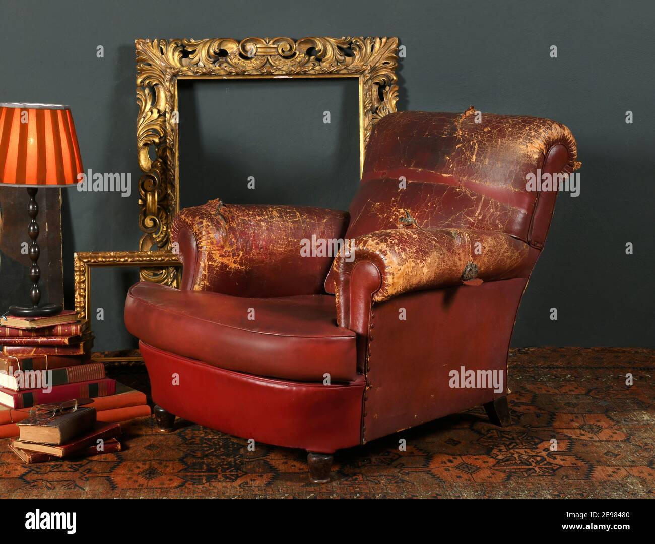 Old shabby red leather armchair placed near vintage decorative frames and  lamp in room with retro style interior Stock Photo - Alamy