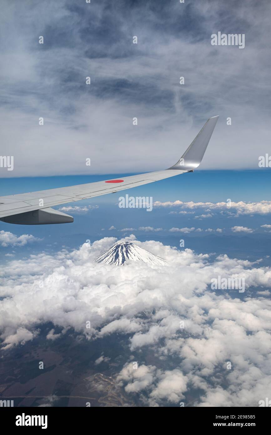 An airplane wing over Mt. Fuji in Japan. Aerial view from passenger window. Stock Photo