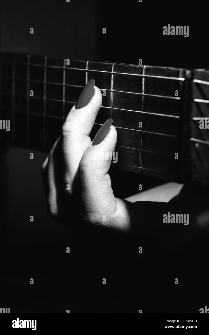 female hand with guitar strings plays closeup monochrome Stock Photo