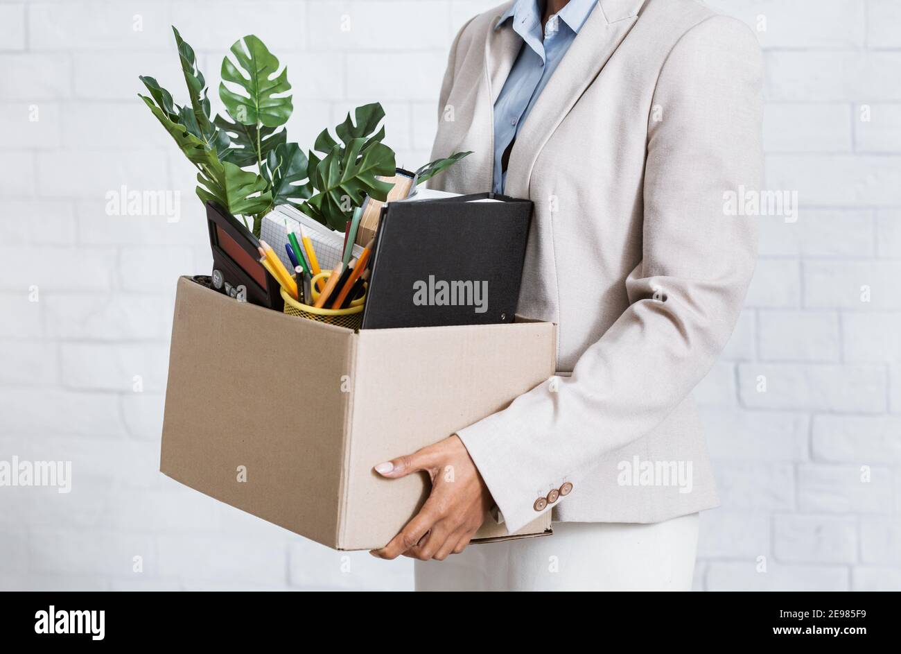 Unrecognizable black woman holding box of personal belongings, leaving office after losing her job, closeup of hands Stock Photo