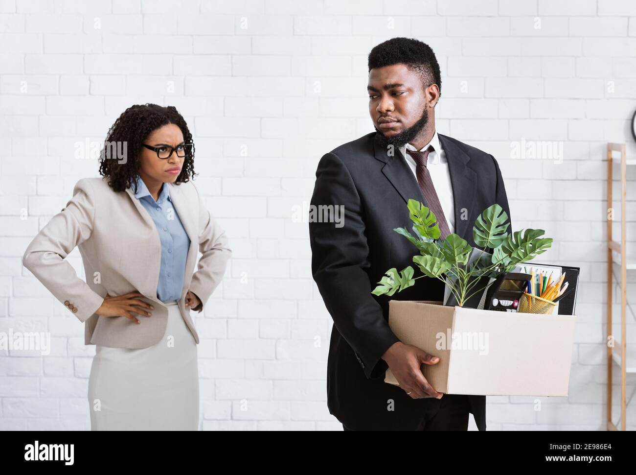 Angry black lady boss firing young male employee at office. Financial crisis and unemployment concept Stock Photo