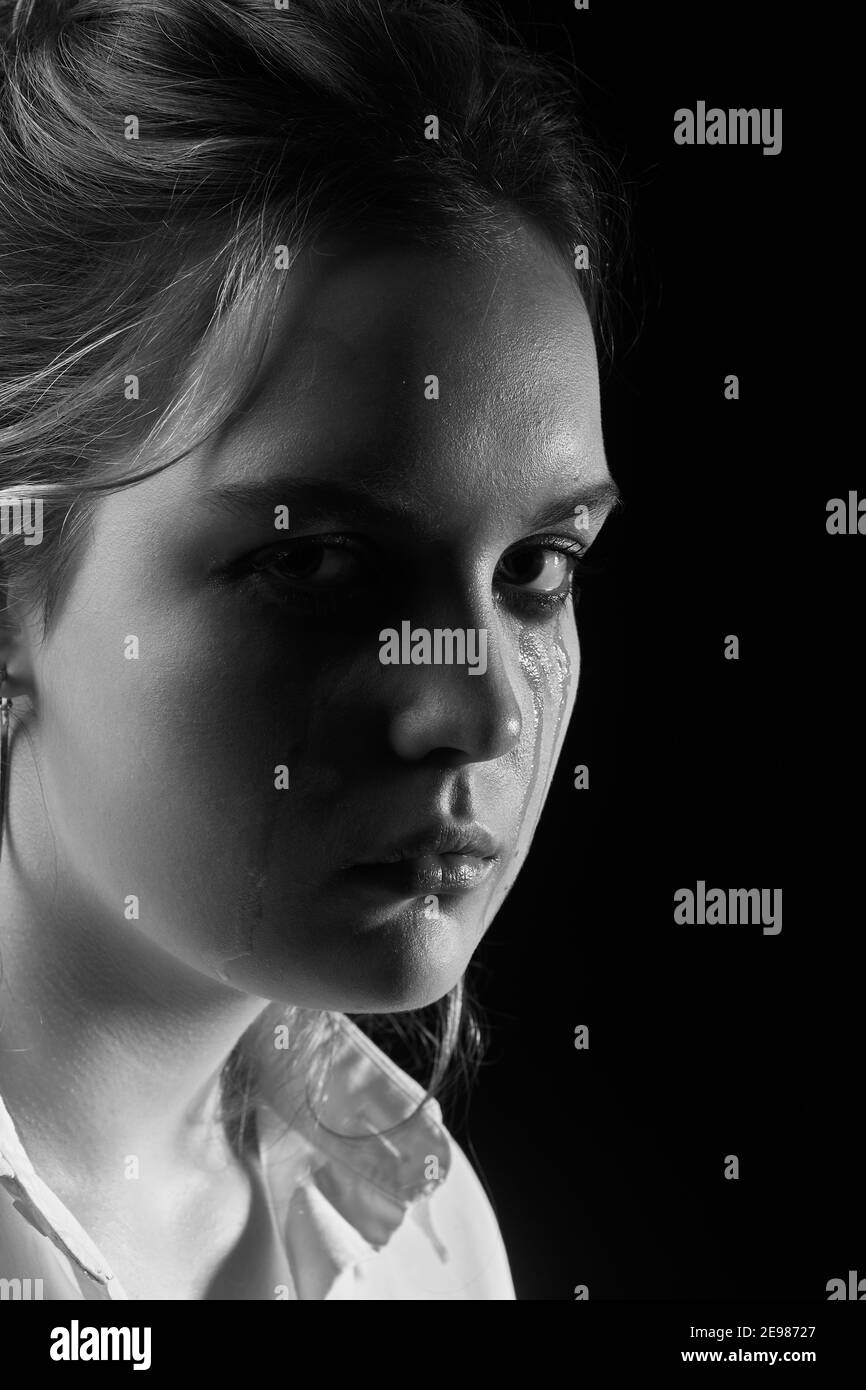 sad woman crying, looking at camera on black background, closeup portrait, monochrome Stock Photo