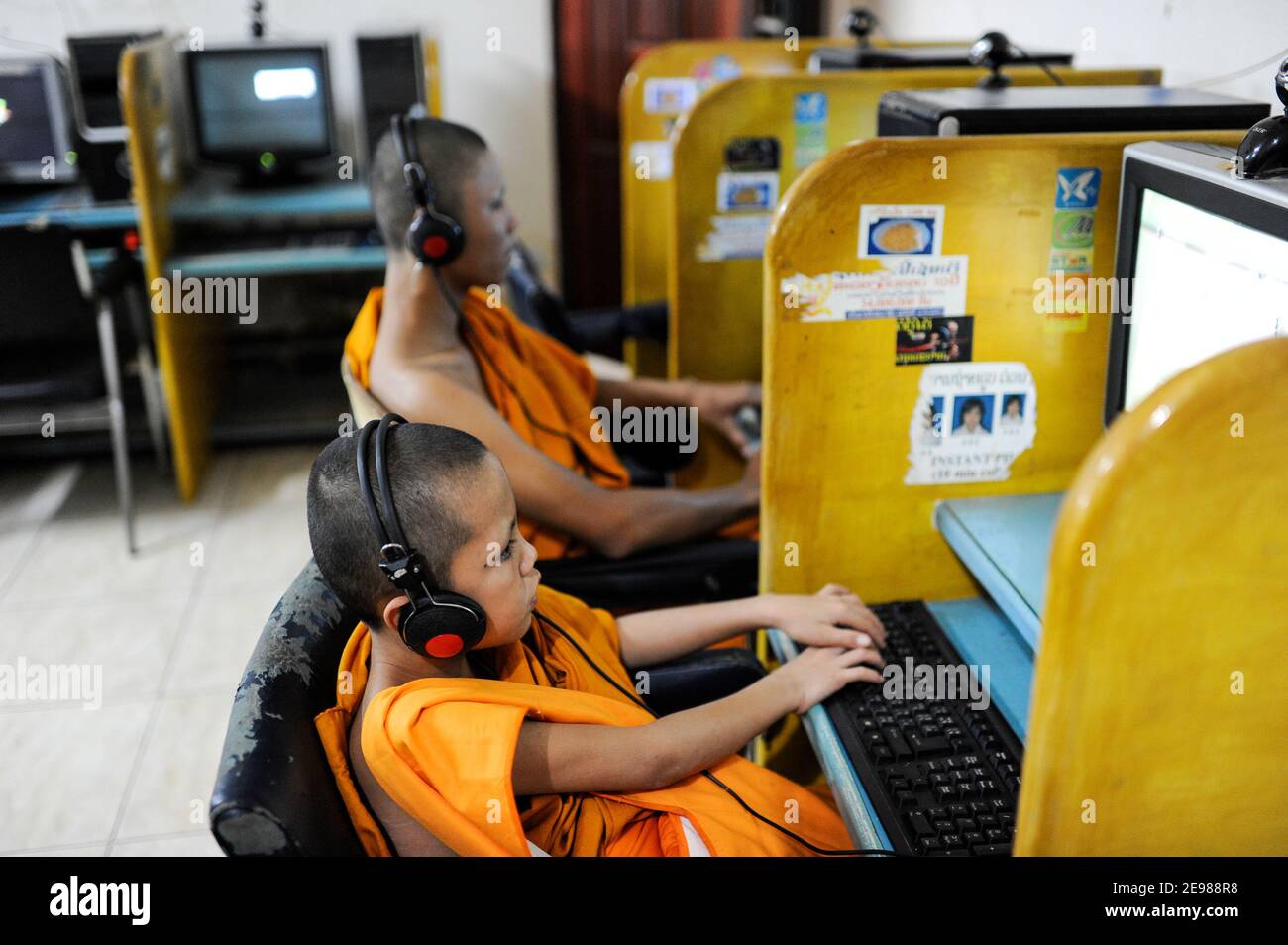 LAO PDR, Vientiane, young buddhist monk in Cybercafe playing games at computer / LAOS Vientiane , junge buddhistische Moenche spielen Computerspiele in einem Internet Cafe Stock Photo