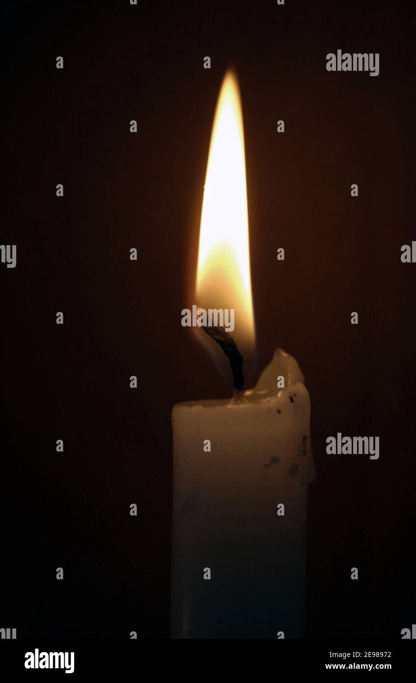 A candle flame burns from its wick melting wax at the same time Stock