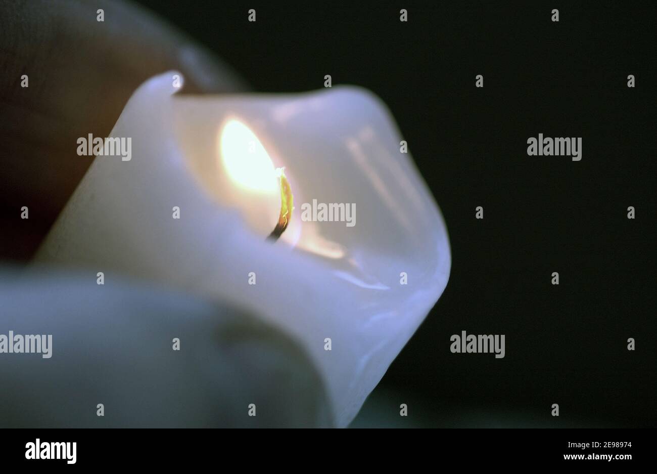A candle flame burns from its wick melting wax at the same time Stock