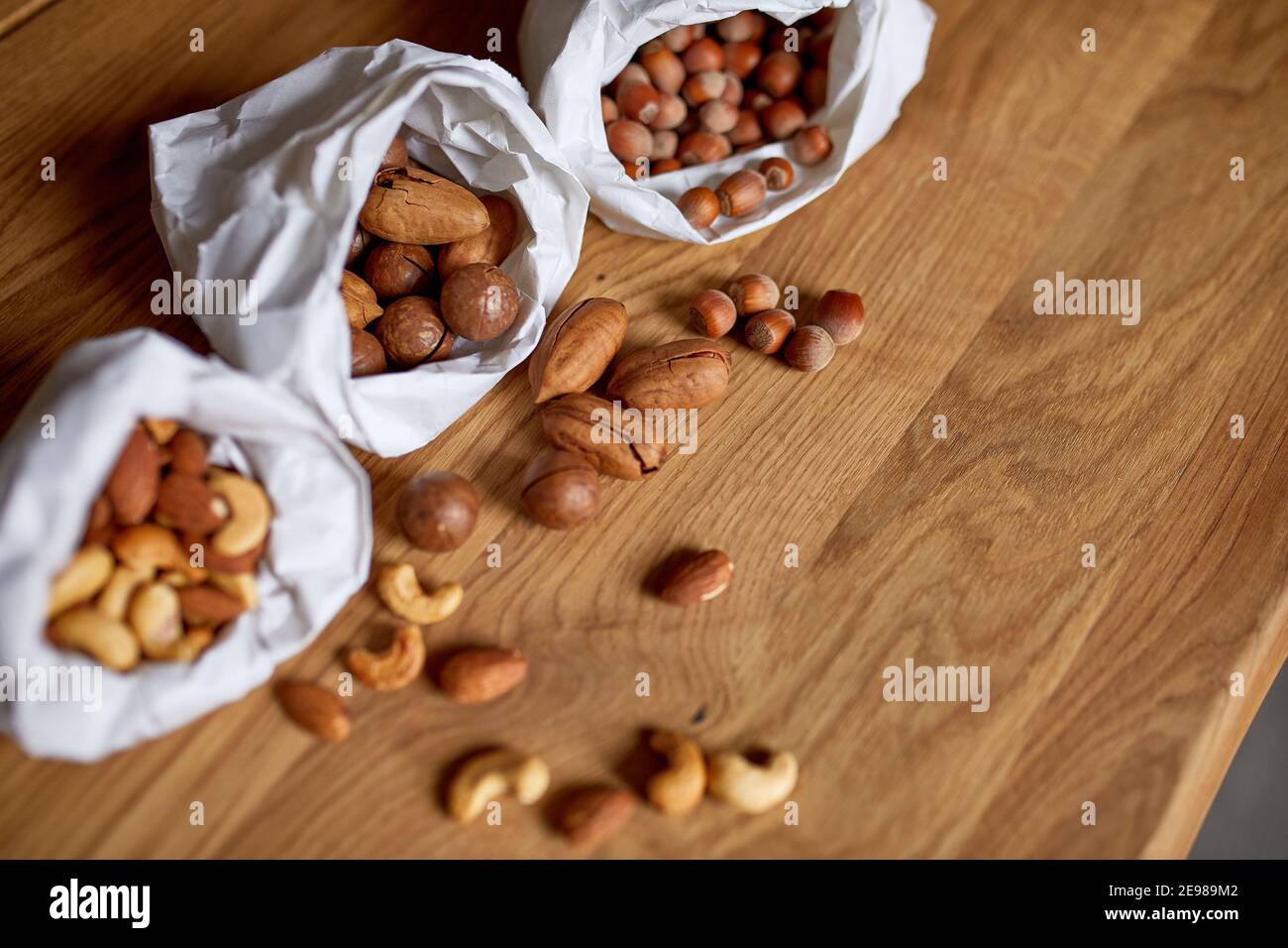 Top view Various sort of nuts on the table in a paper bag on wooden background, shopping grocery concept, nuts delivary, Zero Waste Food Shopping. Cop Stock Photo