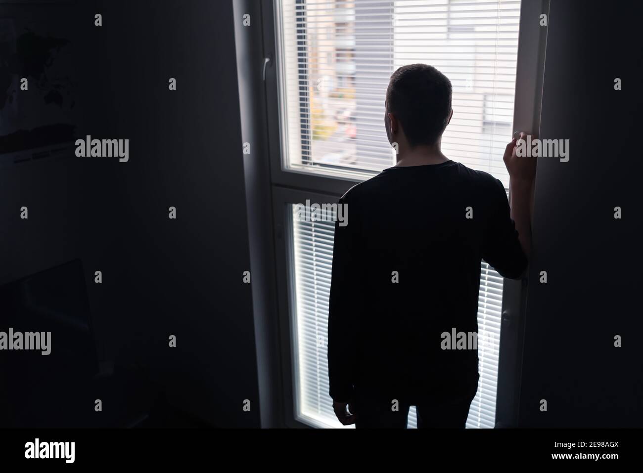 Lonely man looking out the window. Solitude, isolation and loneliness concept. Sad upset person with regret, shame or stress. Stock Photo