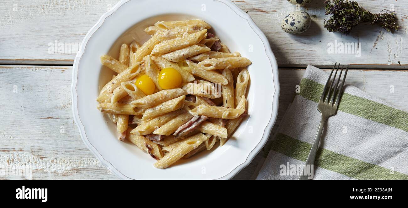 Spaghetti Carbonara, pasta with bacon, egg, hard parmesan cheese and cream sauce. Traditional italian Pasta alla carbonara on white, top view, copy sp Stock Photo