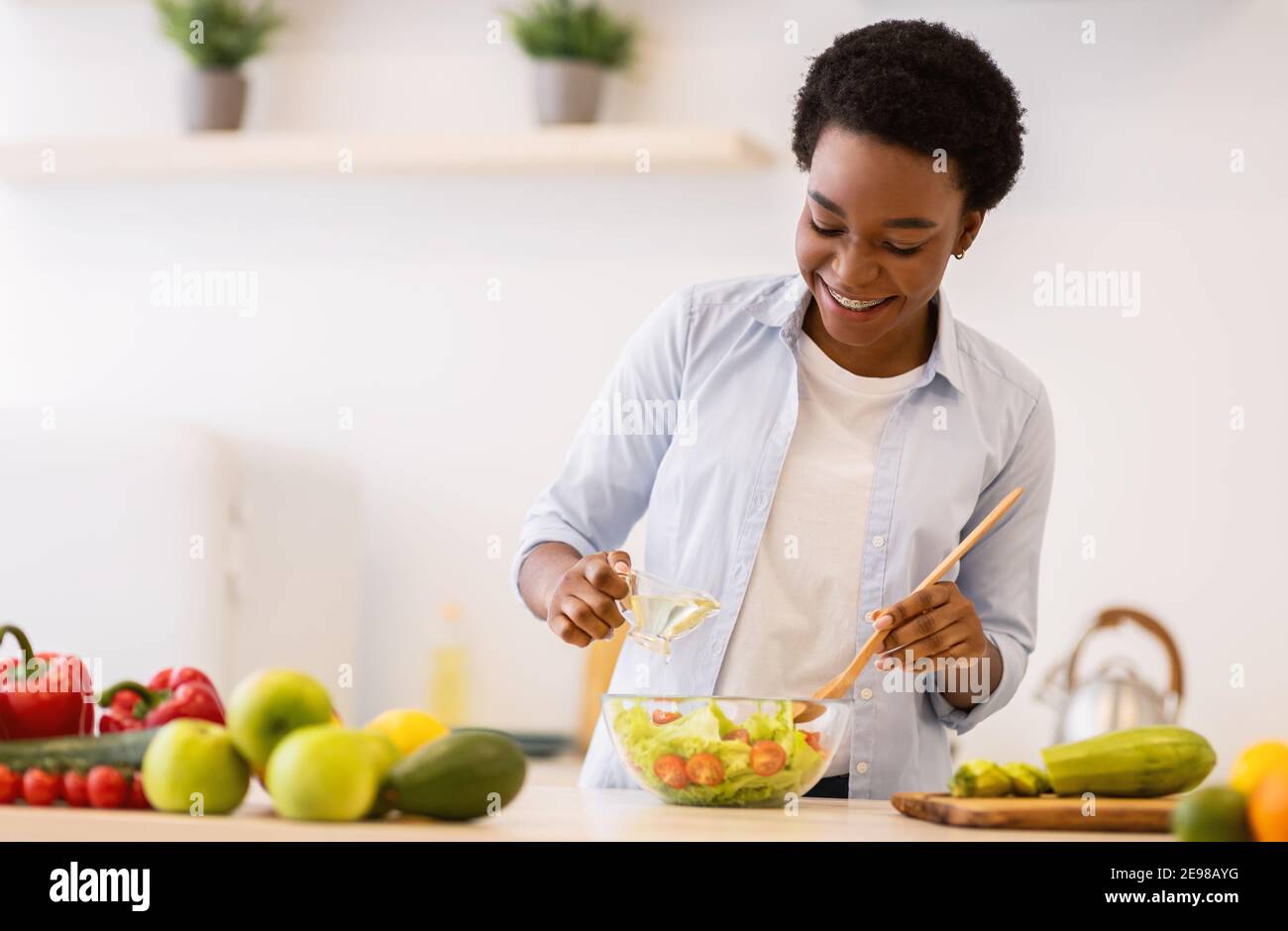 Happy Black Woman Cooking Healthy Vegetable Salad Standing In Kitchen
