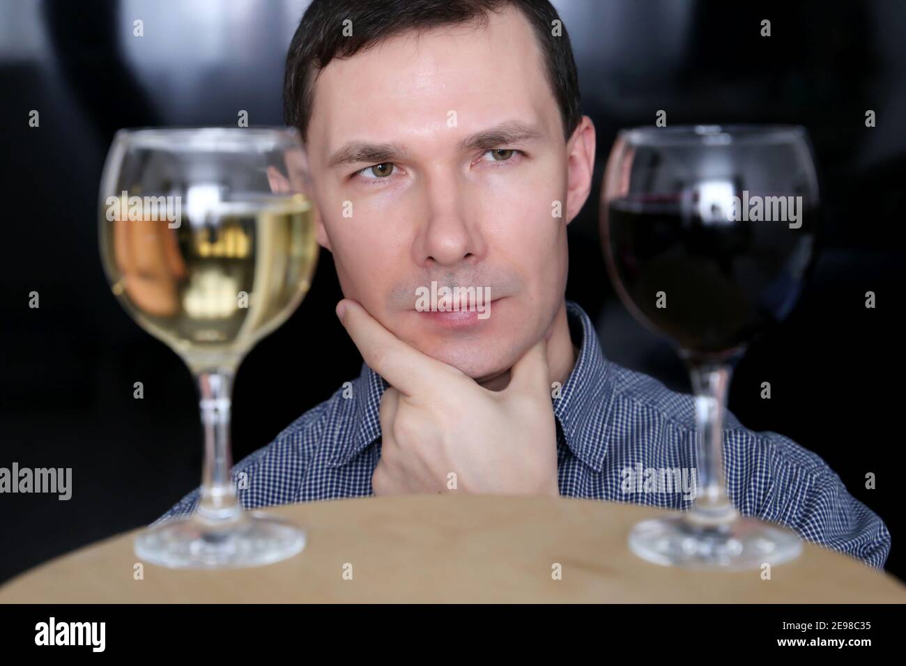 Choosing alcohol, man looks at the glasses with white and red wine. Tasting and party concept Stock Photo