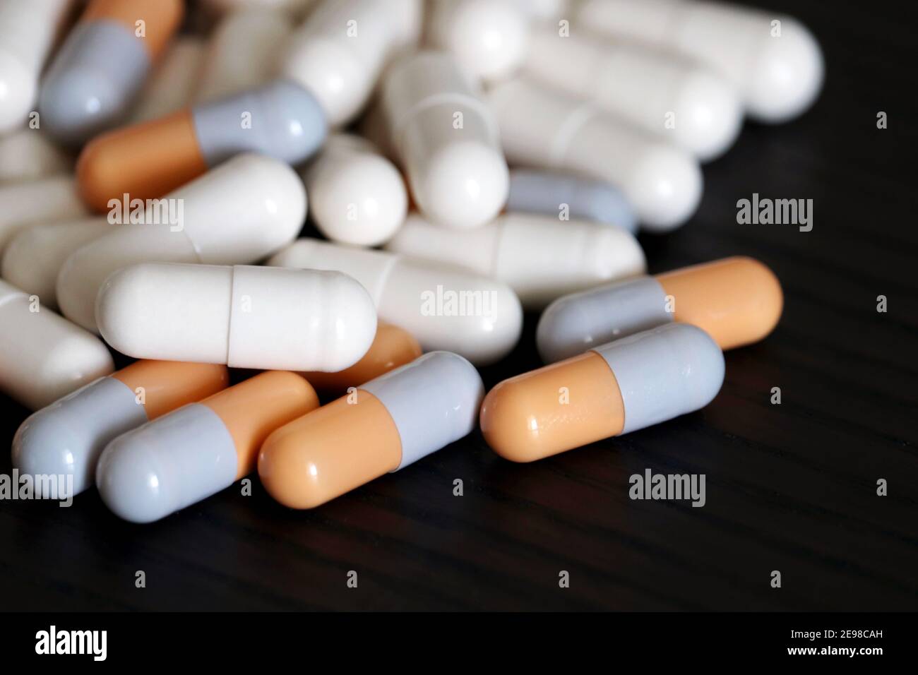 Pills on a dark wooden table, variety of medications in capsules. Background for pharmacy, antibiotics, vitamins Stock Photo