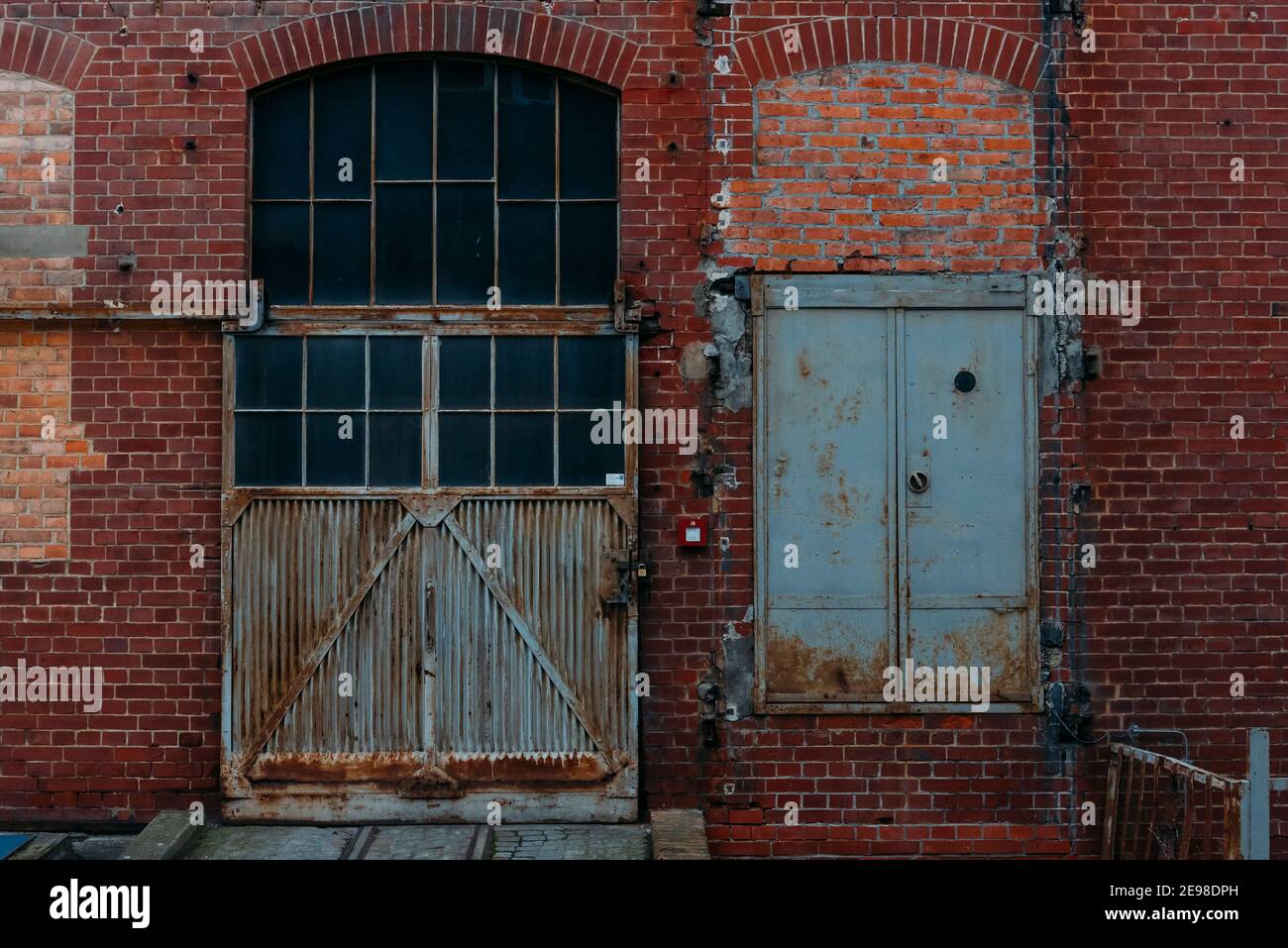 An old rusty gate of an old warehouse, old brick warehouse, brick facade and an old gate Stock Photo
