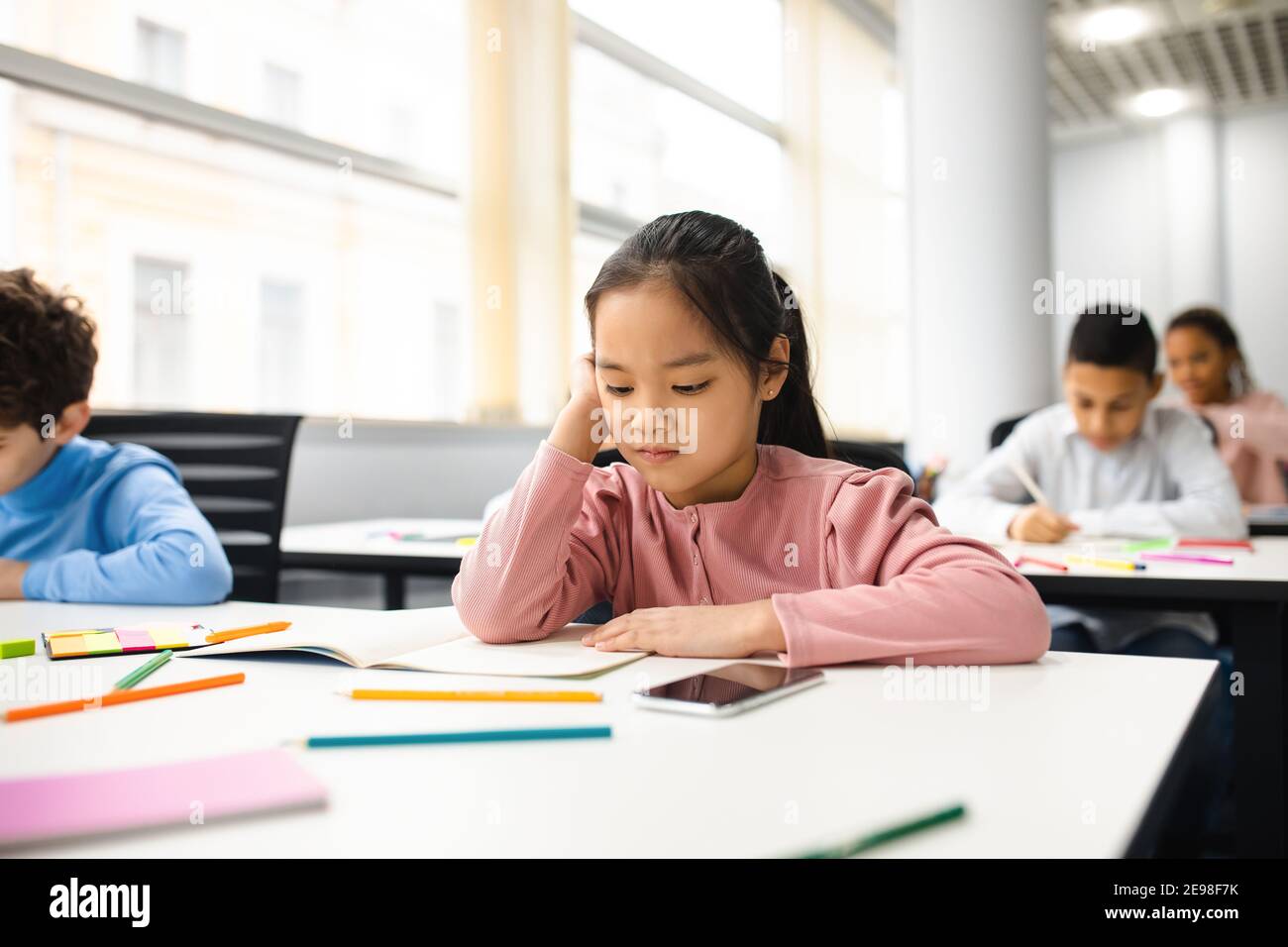 Portrait of small girl sitting at desk in classroom Stock Photo - Alamy