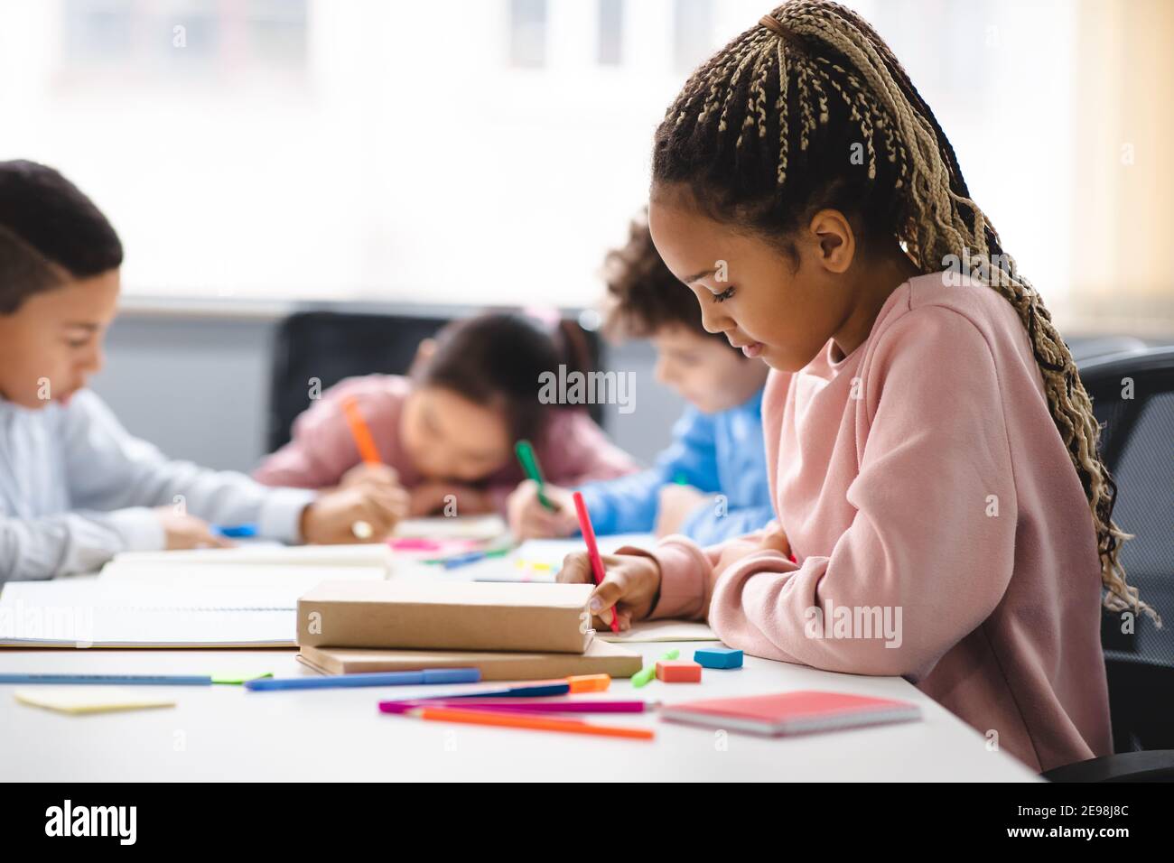 Portrait of small black girl sitting at desk in classroom Stock Photo