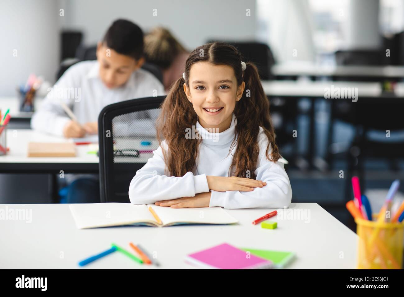 Portrait of small girl sitting at desk in classroom Stock Photo - Alamy