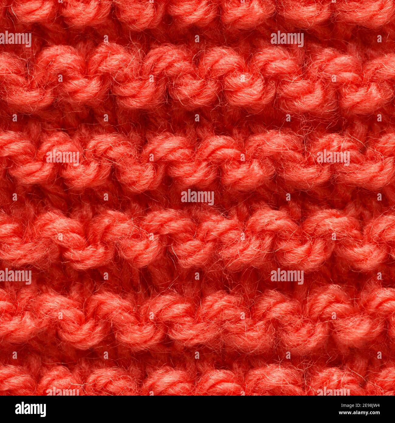 Red knitted fabric seamless pattern for borderless fill. Knitted fabric repeating pattern for background close up. Stock Photo