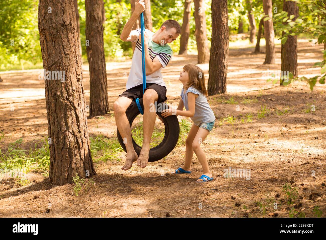 Happy child daughter pushing father on tire swing in autumn garden. High quality photo Stock Photo