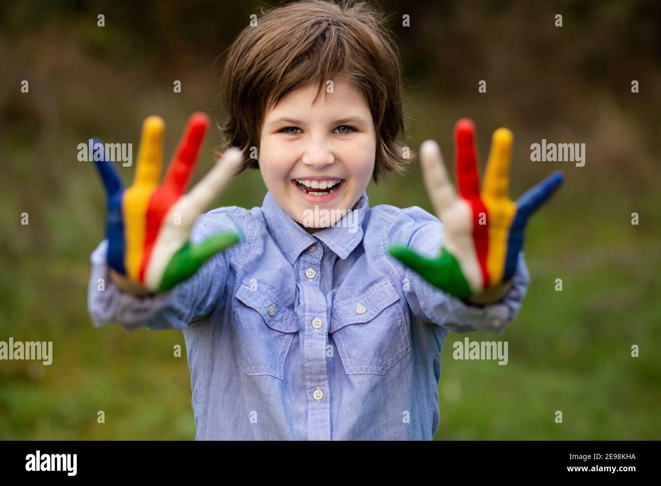 Outdoor portrait of cheerful kid girl show hello gesture with hands painted in Seychelles flag colors Stock Photo