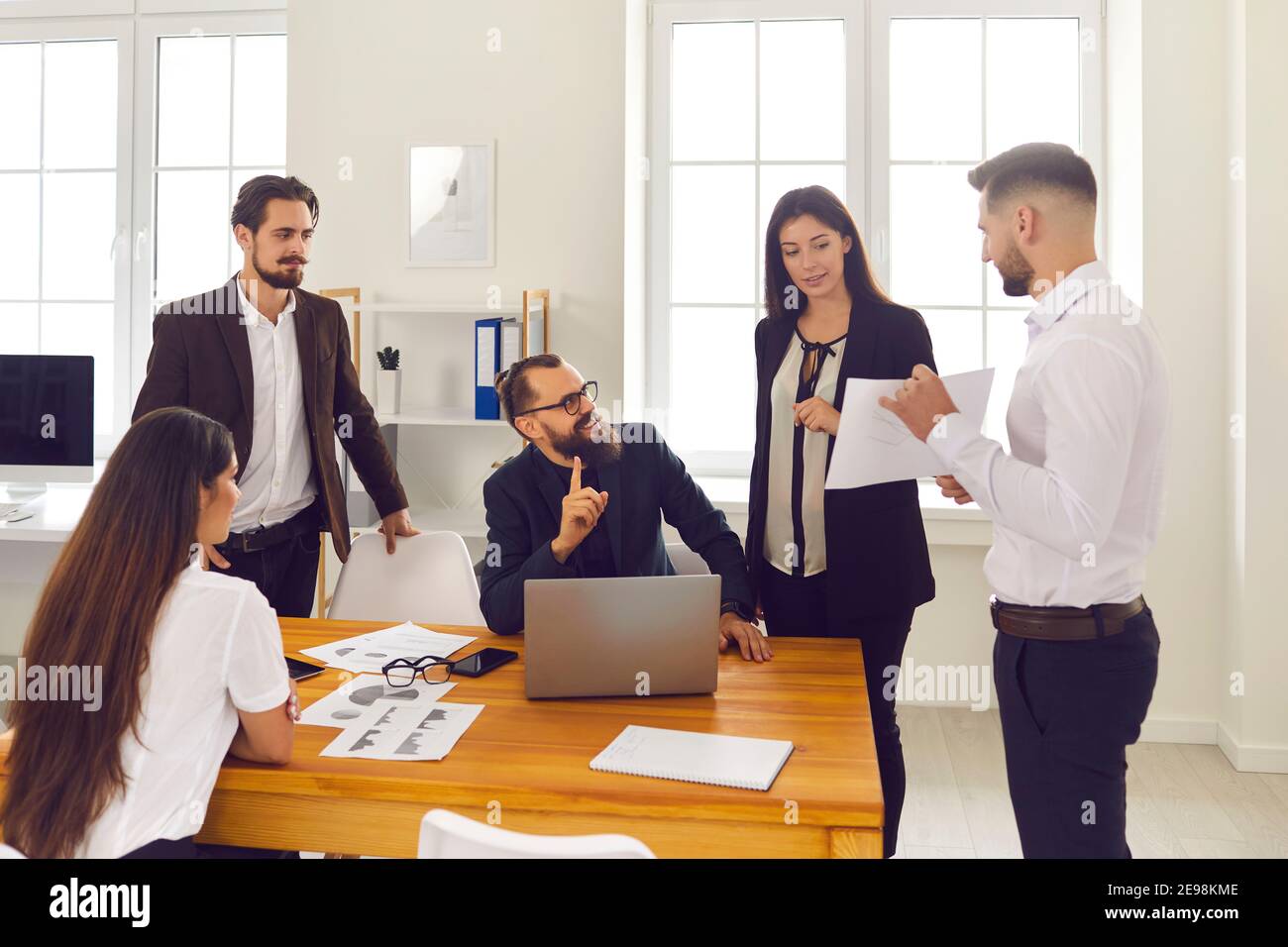 Group of young company employees discussing work matters and analyzing sales data Stock Photo