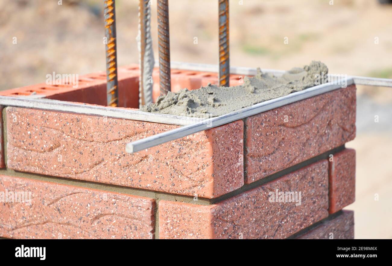 Bricklaing brick pillar with iron bars. Stock Photo