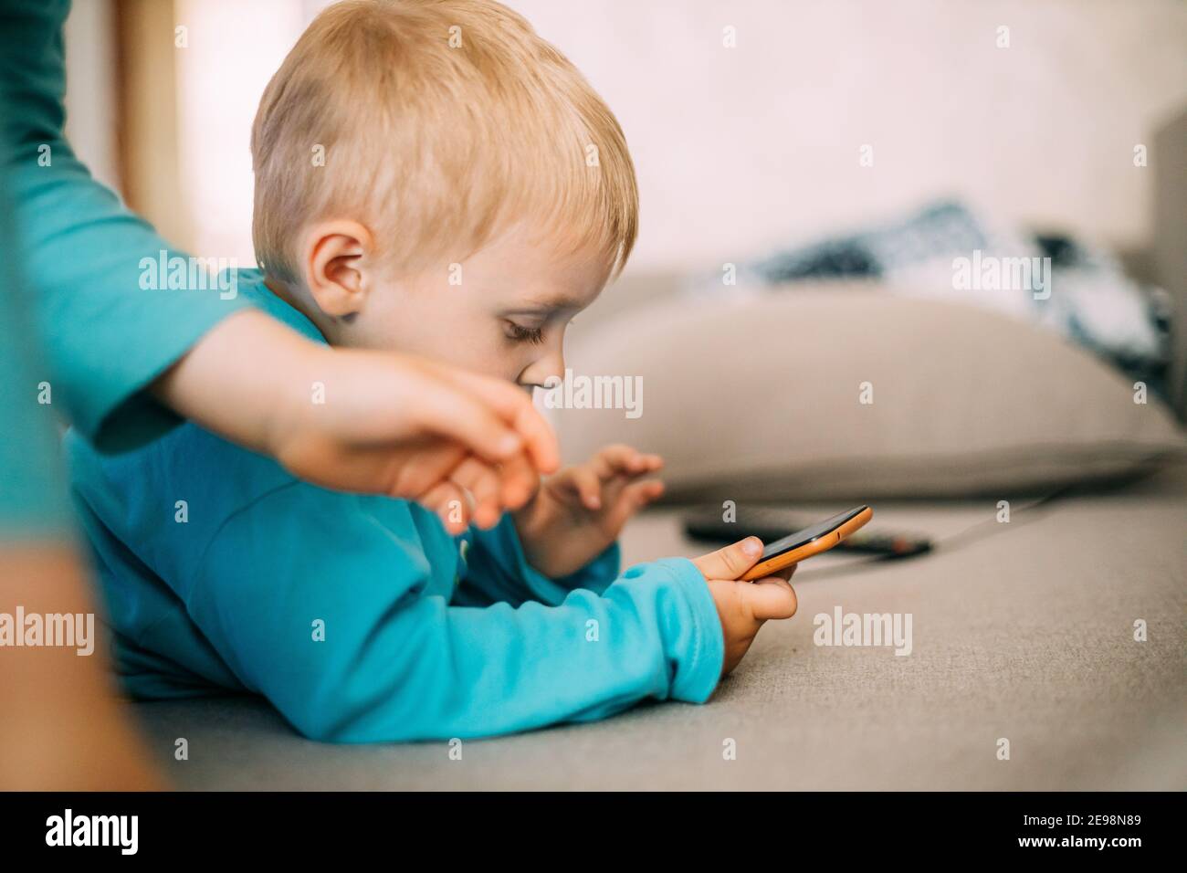 Little Caucasian Boy Playing Games On Phone Thoughtfully Stock Photo
