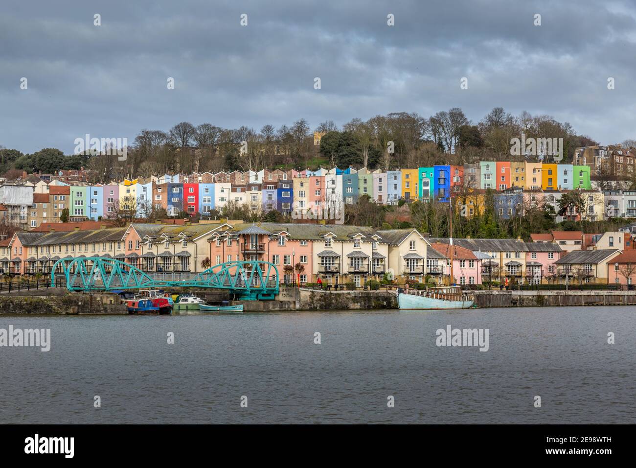 View looking across the River Avon in Bristol, England, towards modern riverside apartments, and colourful older terraced houses behind. Stock Photo