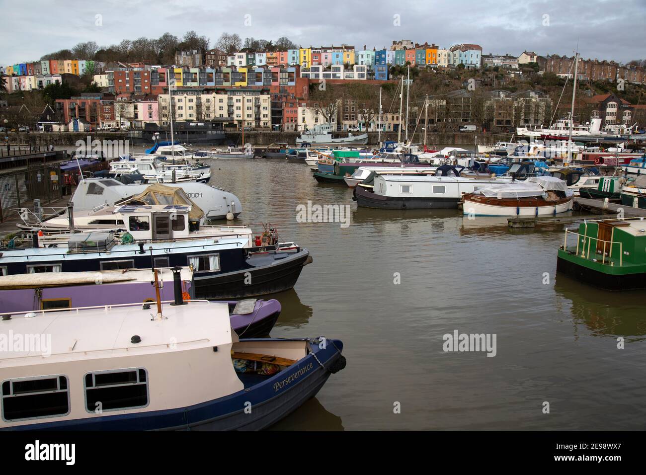 Amarina or wharf on the River Avon in Bristol, England. A variety of boats with colourful houses on a hill in the distance. Stock Photo