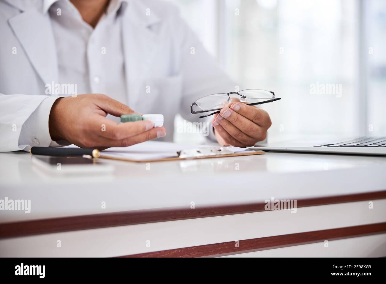 Optical dispenser sitting at the table in his office Stock Photo Alamy