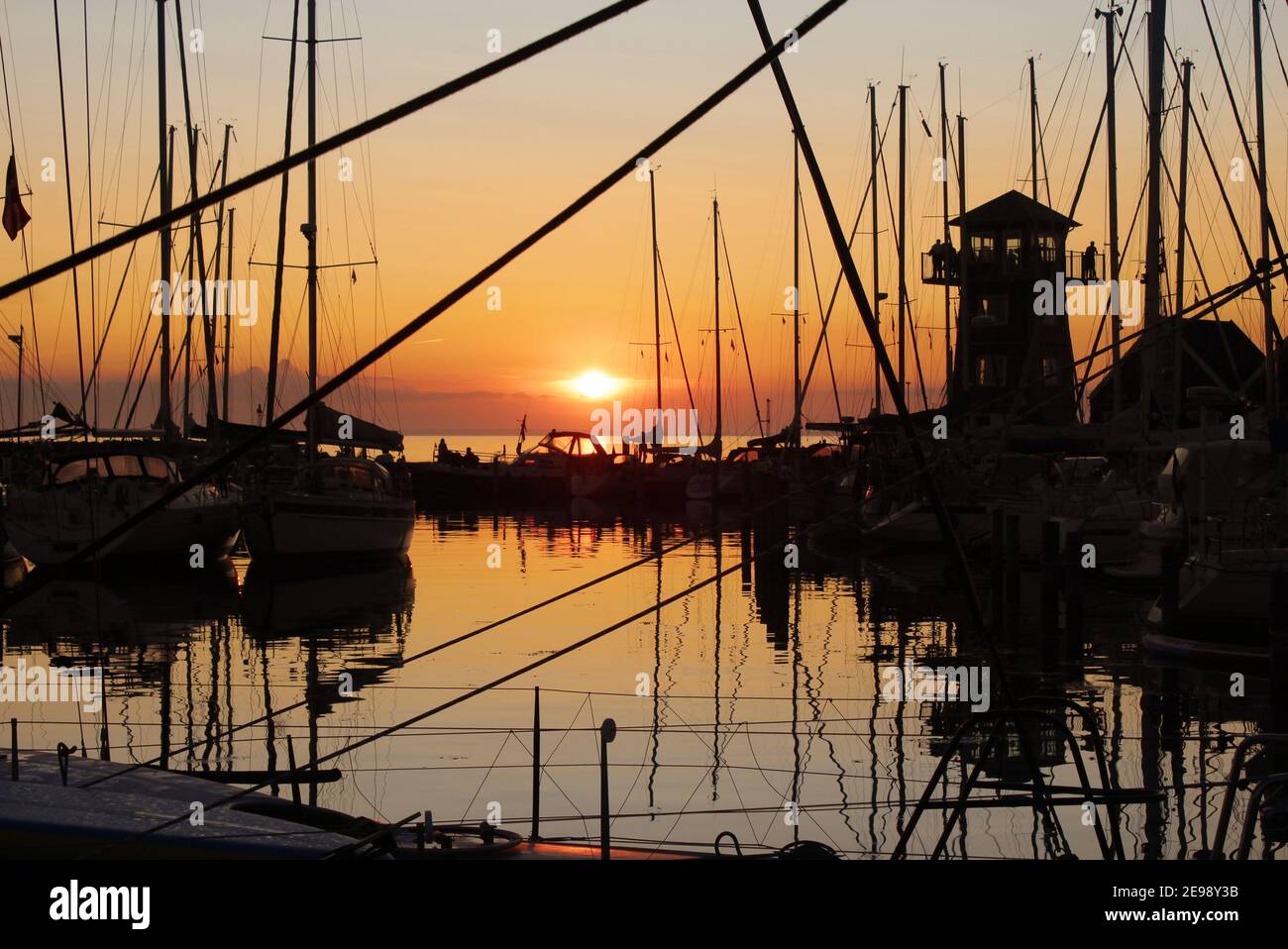 Beautiful summer sunset behind the busy yacht marina of Bagenkop harbour. On the island of Langeland in Denmark. Stock Photo