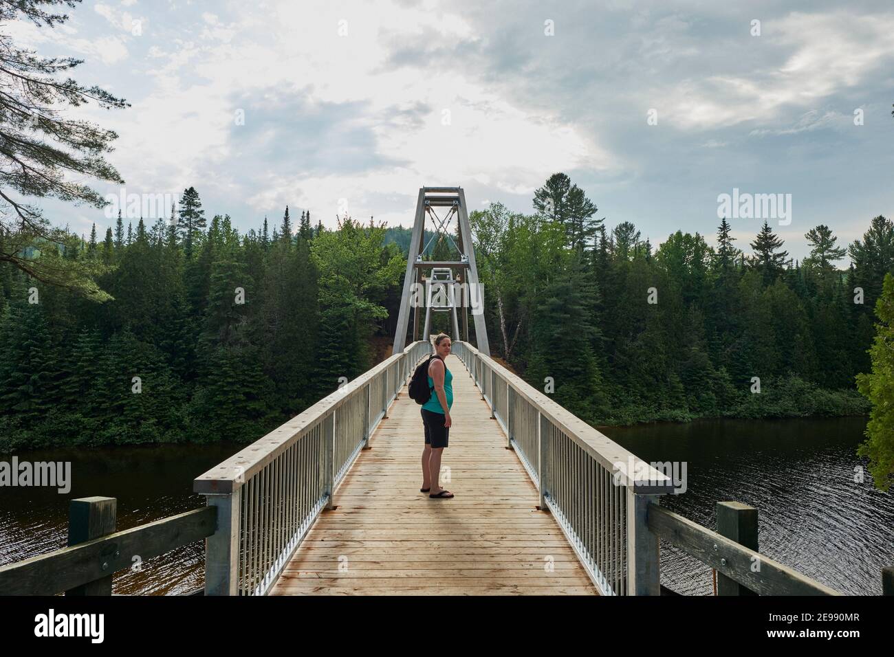 Female hiker walking across bridge in Mauricie National park, shawinigan, Quebec, Canada Stock Photo