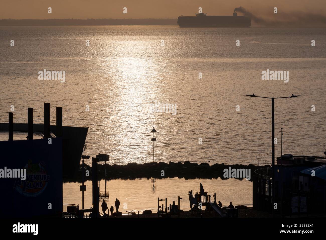 Southend on Sea, Essex, UK. 3rd Feb, 2021. HMM Le Havre is seen passing Southend on Sea on the Thames Estuary late afternoon after leaving DP World London Gateway port. The Algeciras class container ship is one of the largest ever built, entering service in August 2020, able to carry nearly 24000 containers, and serves the Far East Europe 3 loop route. The UK is applying to join the Comprehensive and Progressive Agreement for Trans-Pacific Partnership - or CPTPP – which includes Far Eastern countries served by giant ships such as this. Passing lagoon play area with family Stock Photo