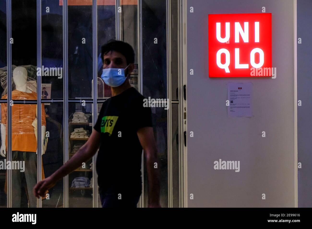 A man wearing a face mask walks past a closed Uniqlo boutique in Malaysia  Stock Photo - Alamy