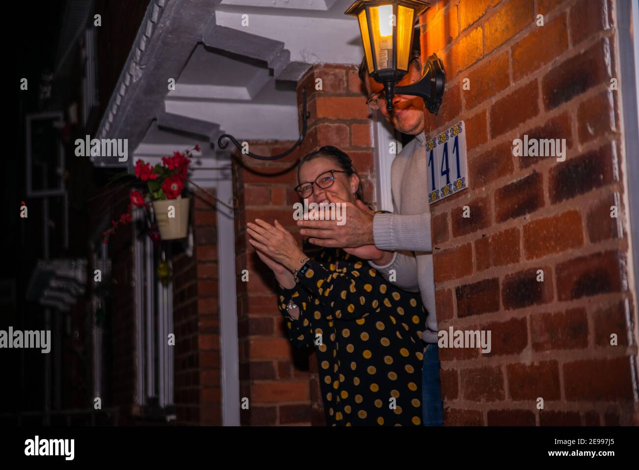 Birmingham, West Midlands, UK. 3rd February 2021: A couple come out of their house to clap from their doorstep at 6PM, after Boris Johnson called for the nation to pay respects to Captain Tom Moore who passed away at the age of 100 on Tuesday, after a fight with Covid-19. Credit: Ryan Underwood / Alamy Live News Stock Photo