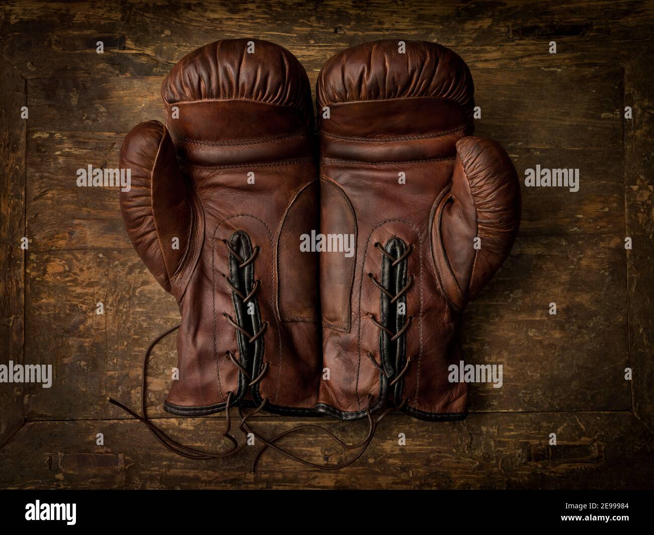 Pair of old brown leather boxing gloves lying on an antique wooden table Stock Photo