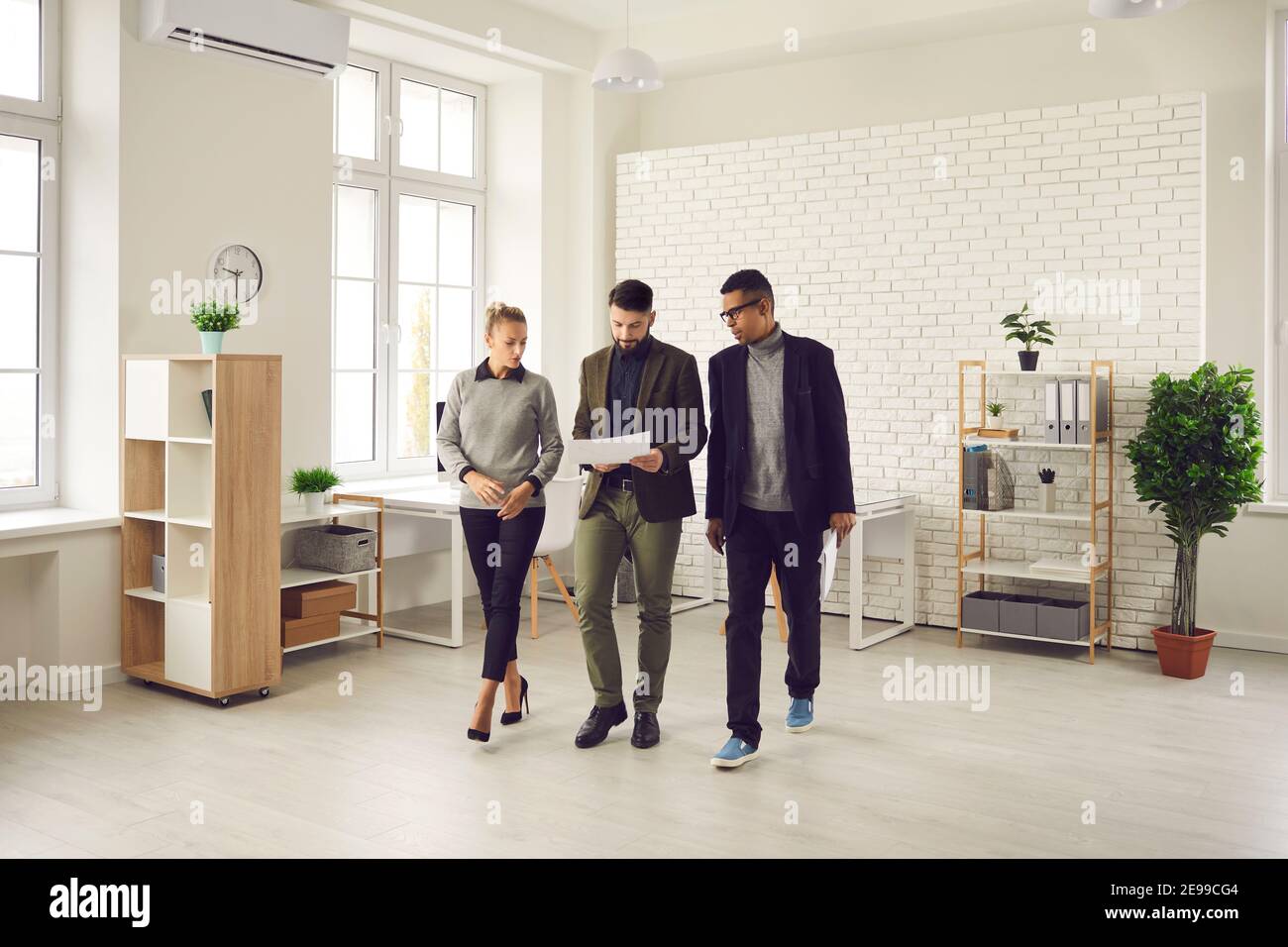 Office workers on the go review documents and discuss new business development strategies and plans. Stock Photo