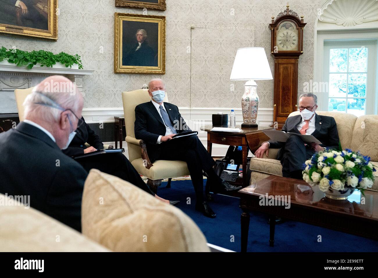 President Joe Biden, center, wears a protective mask while meeting with U.S. Vice President Kamala Harris, not pictured, Senate Majority Leader Chuck Schumer (D-N.Y.), right, and fellow Democratic Senators to discuss the American Rescue Plan in the Oval Office of the White House in Washington on Wednesday, February 3, 2021. Credit: Stefani Reynolds/Pool via CNP /MediaPunch Stock Photo