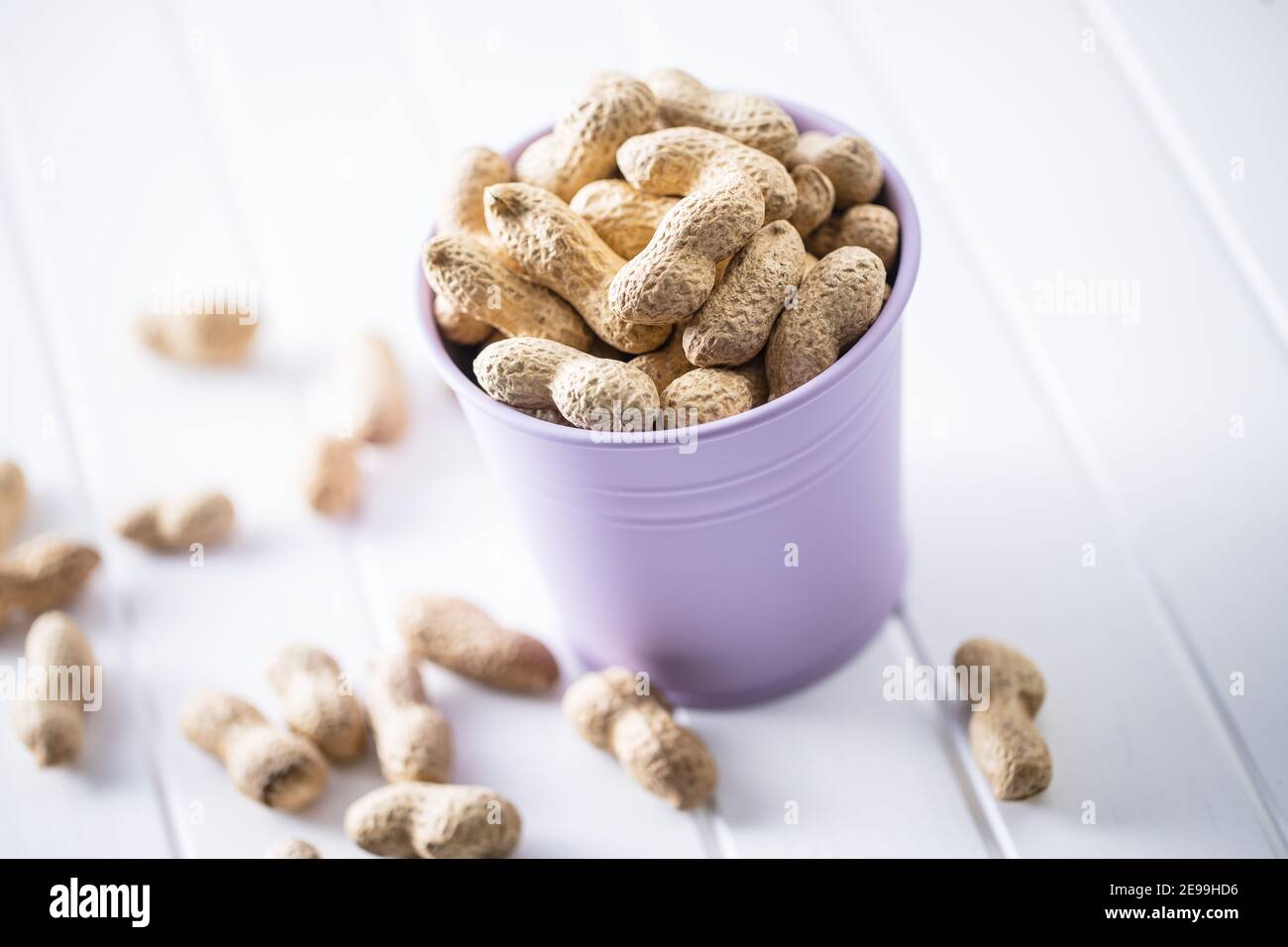 Roasted peanuts. Tasty groundnuts in cup on white table. Stock Photo