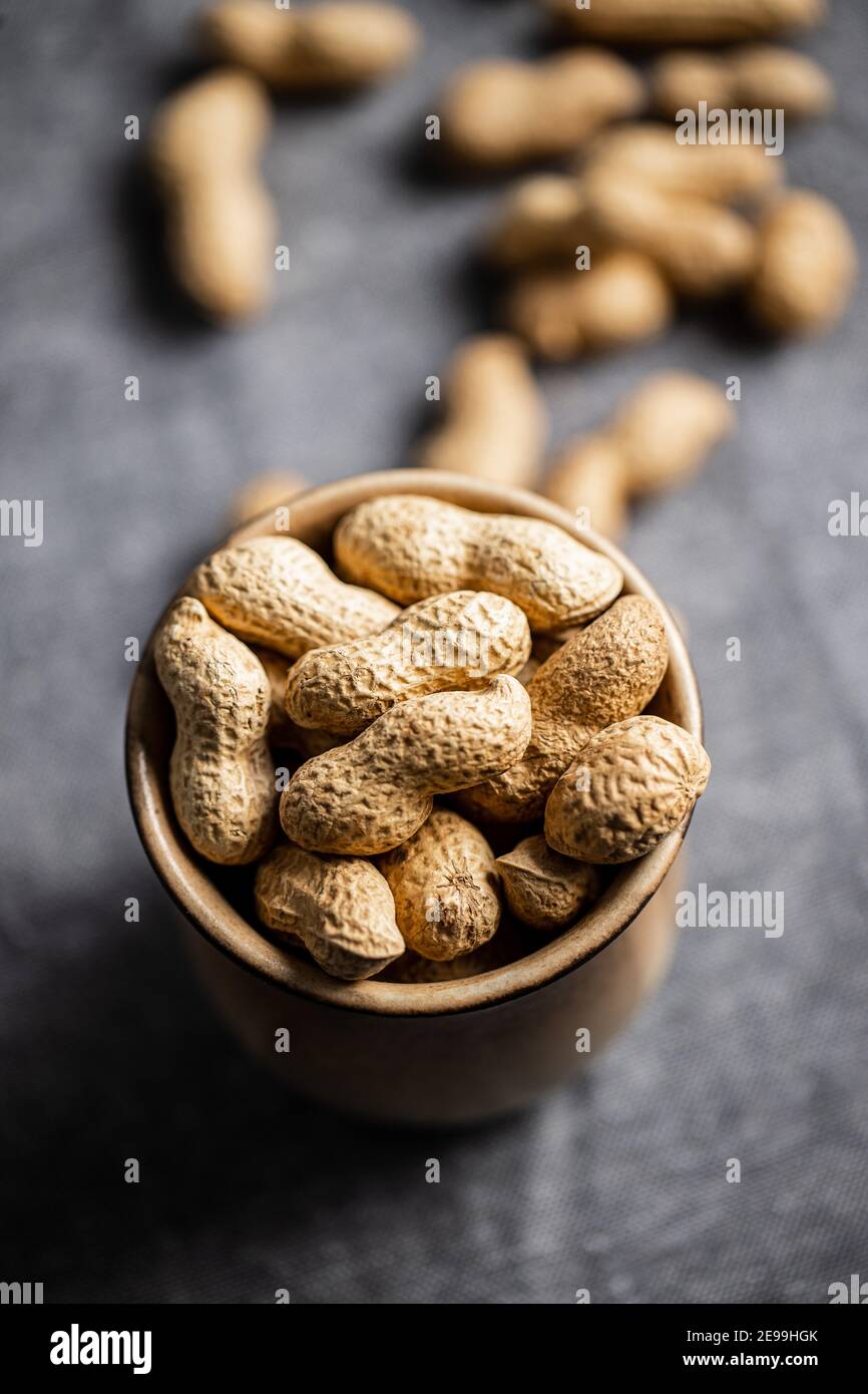 Roasted peanuts. Tasty groundnuts in cup on tablecloth. Stock Photo