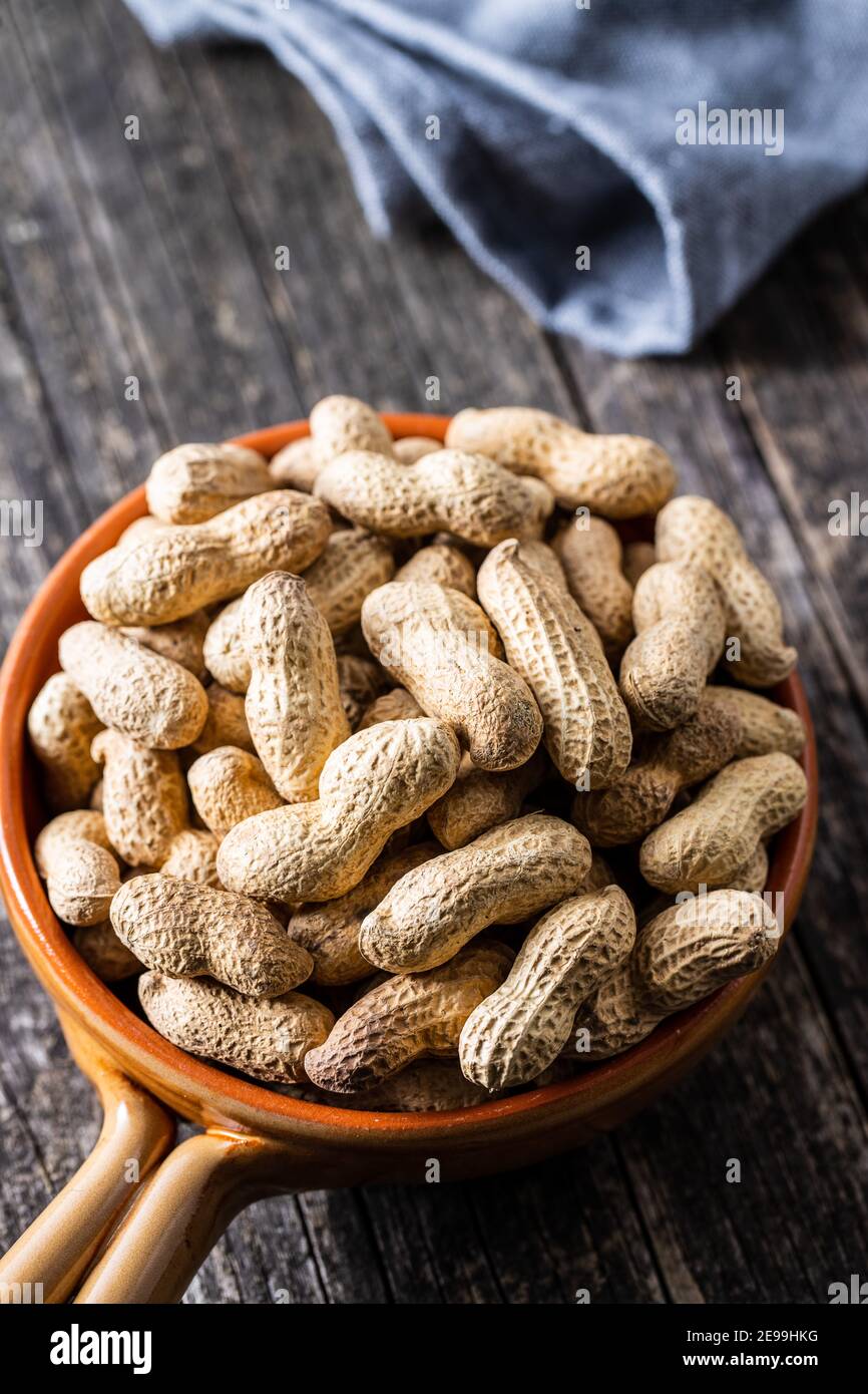 Roasted peanuts. Tasty groundnuts in pot on wooden table Stock Photo ...